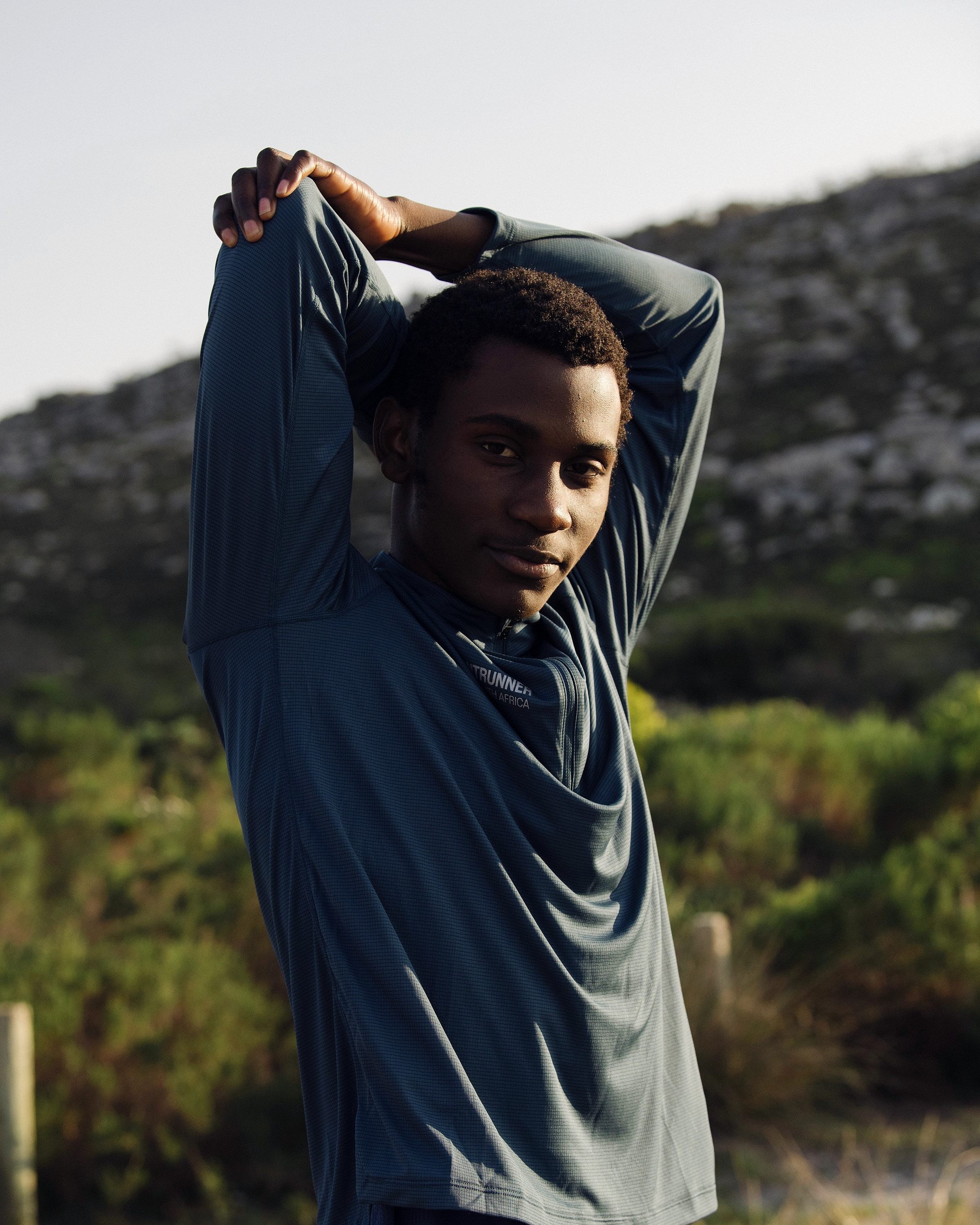 Alexander Hwande stretching his arms overhead before a run