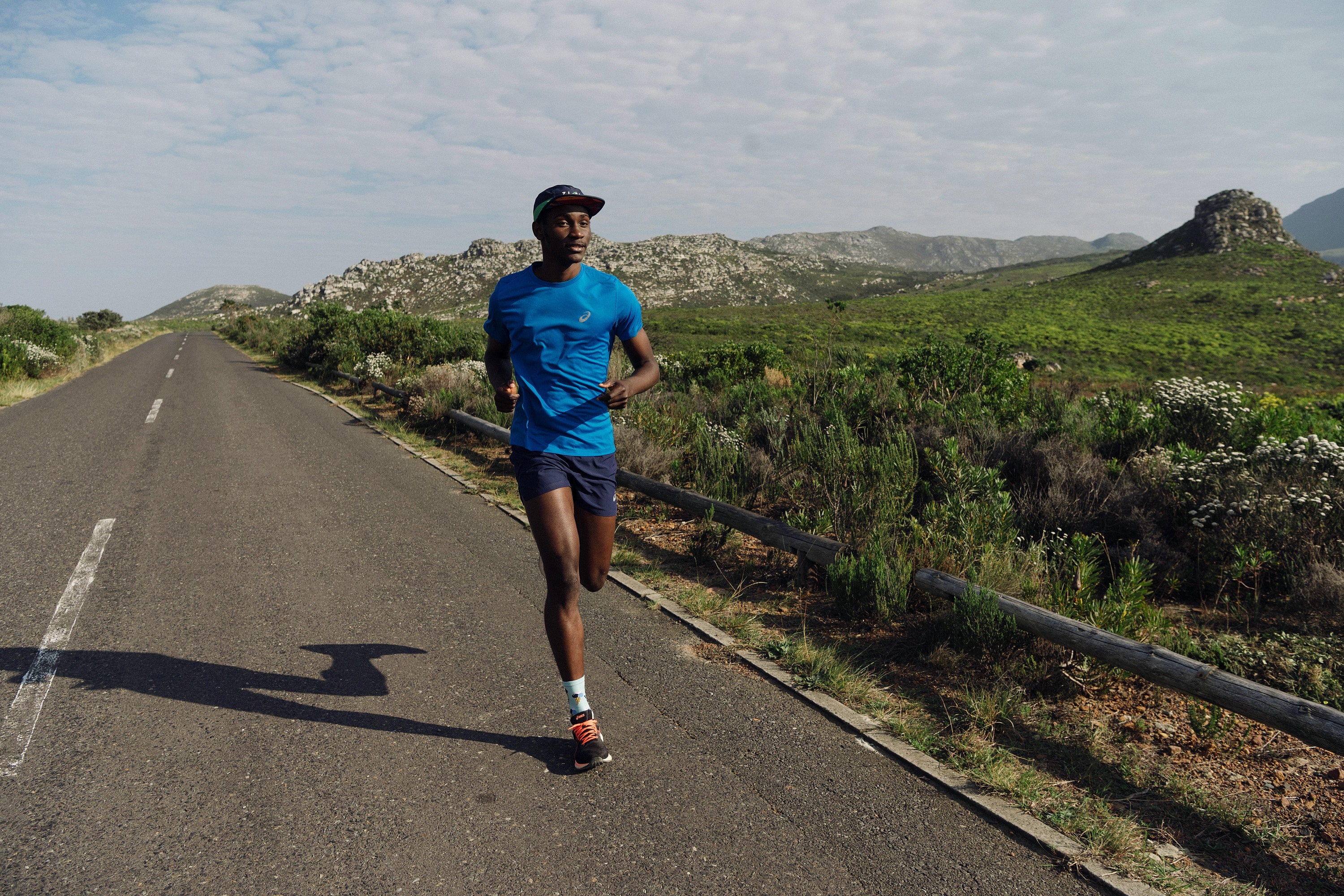 Alexander Hwande running towards the camera on a quiet road through the mountains