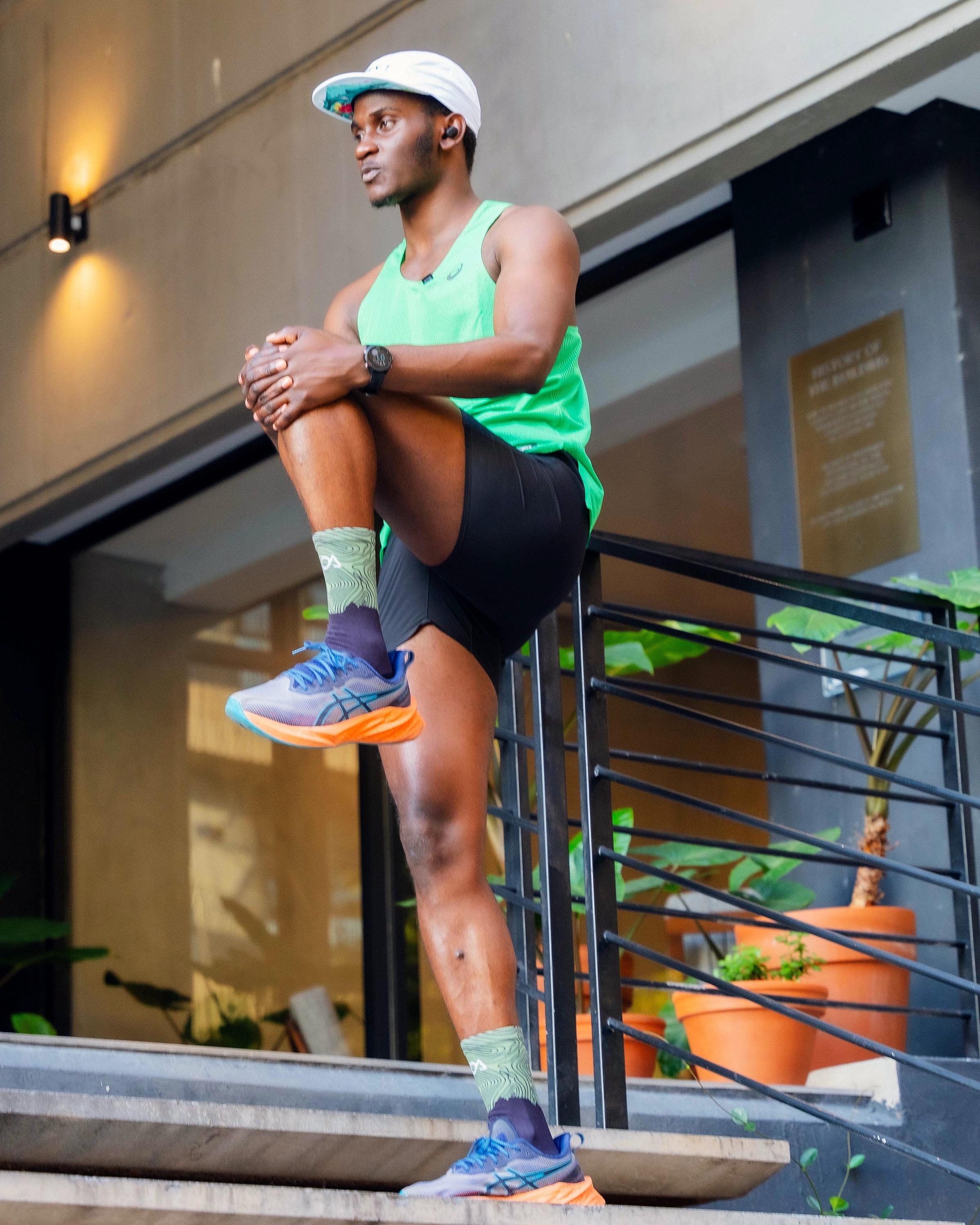 Alexander Hwande warming up on a flight of steps, pulling one knee to his chest