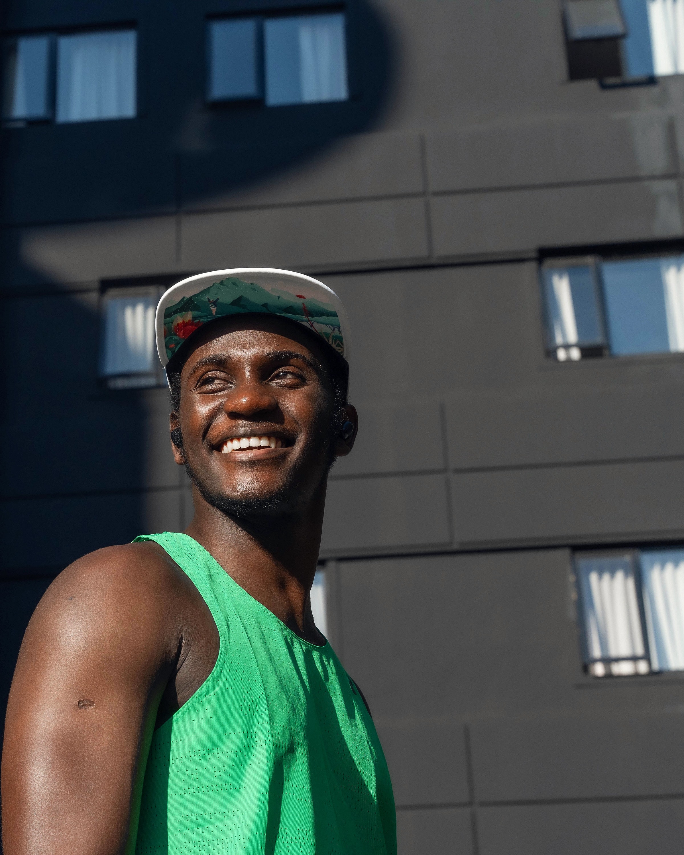Alexander Hwande in a running vest and cap, smiling over his shoulder