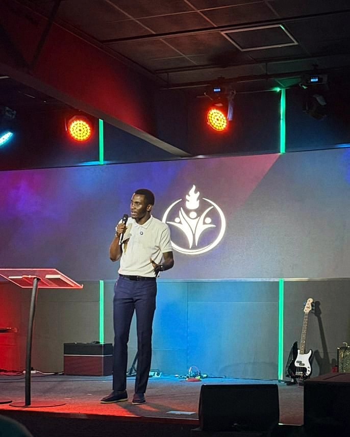 Alexander Hwande speaking on a church stage with a microphone in his hand