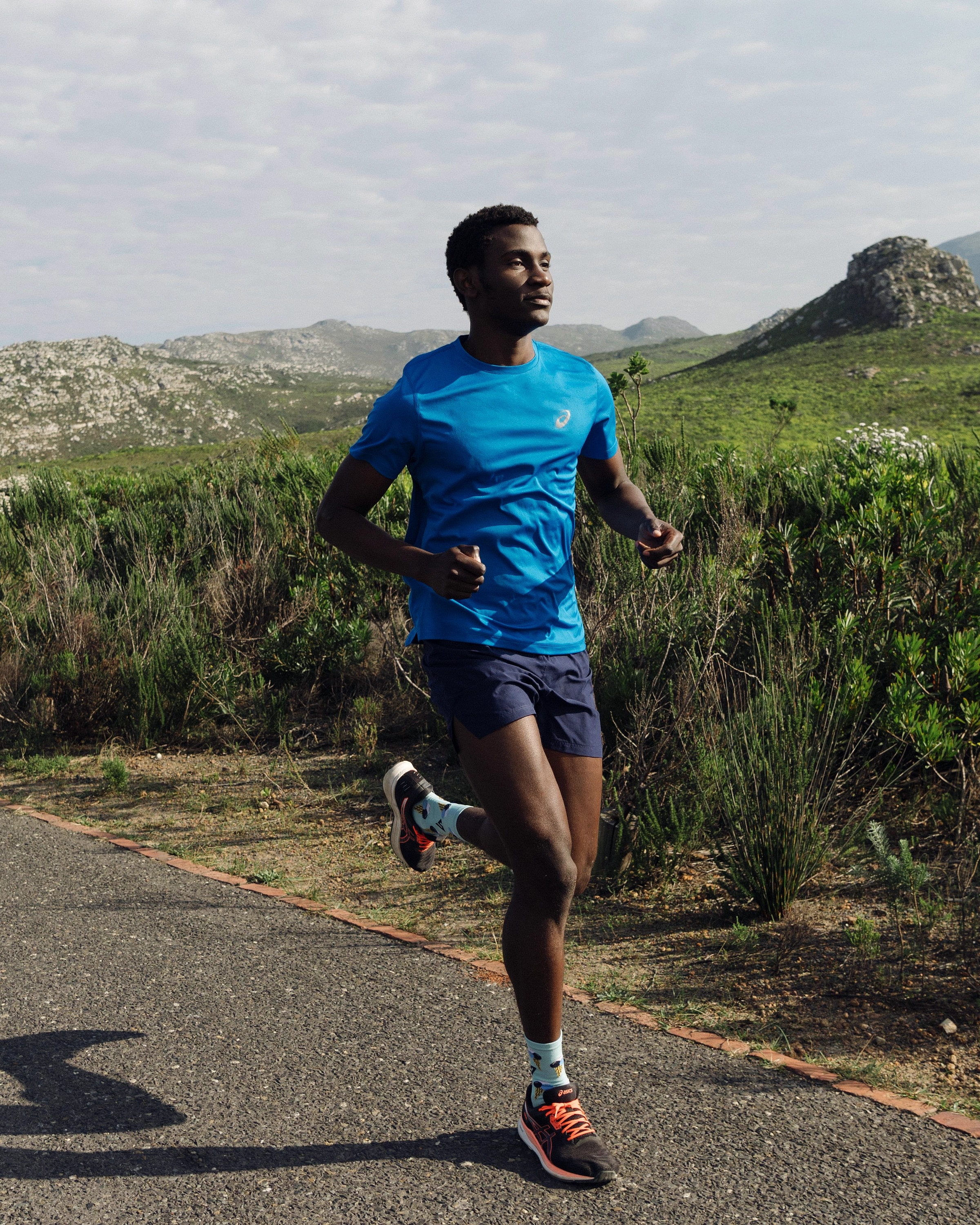 Alexander Hwande running alone on a quiet road through the mountains