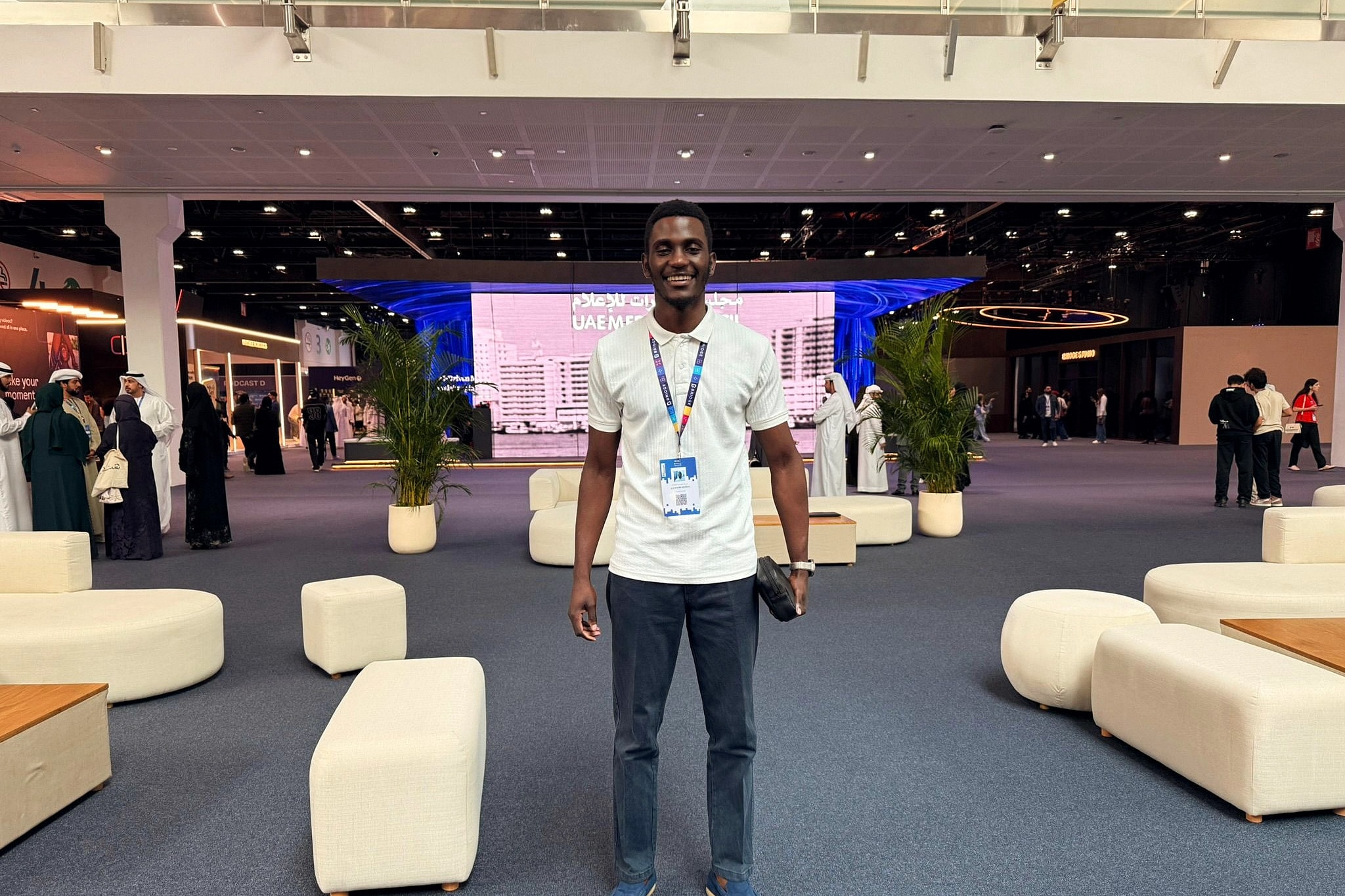 Alexander Hwande standing in the main hall of a summit, wearing a delegate pass